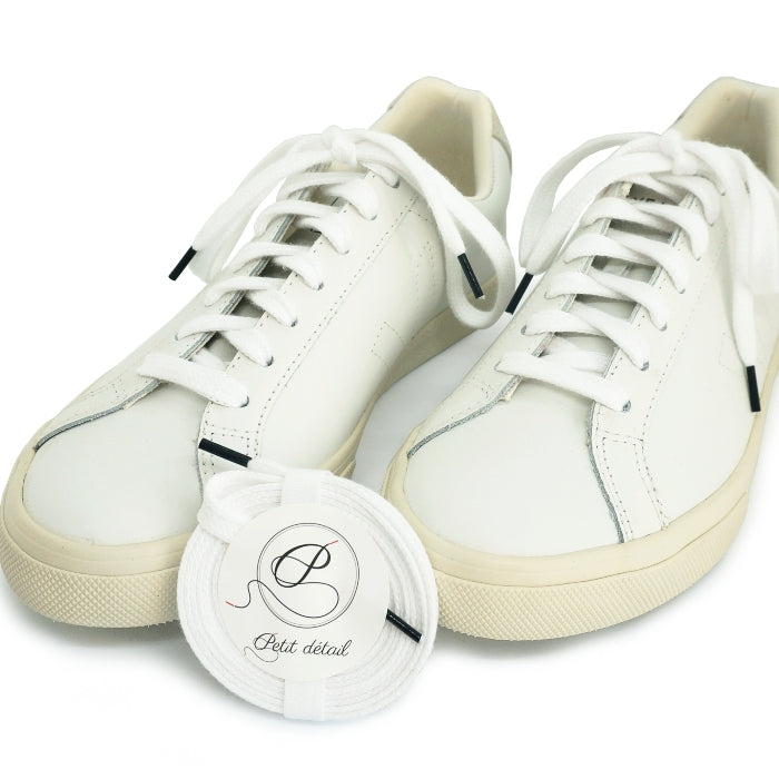 Lacets en coton biologique certifié GOTS Blanc et Noir Cobalt - paire emballée avec une autre paire mise en scène sur des sneakers - Paire faisant partie d’un ensemble Lacets Made in France et Bouton de Manchette - vue de face - Petit-détail.com 